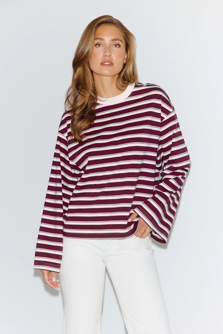 Een bordeauxrood-wit gestreept shirt met lange mouwen en een witte broek.