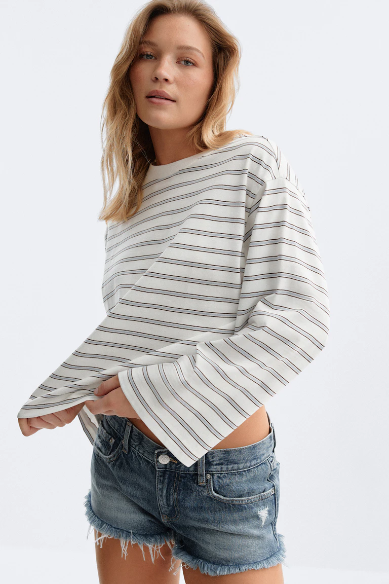 ID 310064, StyleColorSupplier 12651: Hvit, stripete topp med lange ermer og blå denimshorts med slitt utseende.