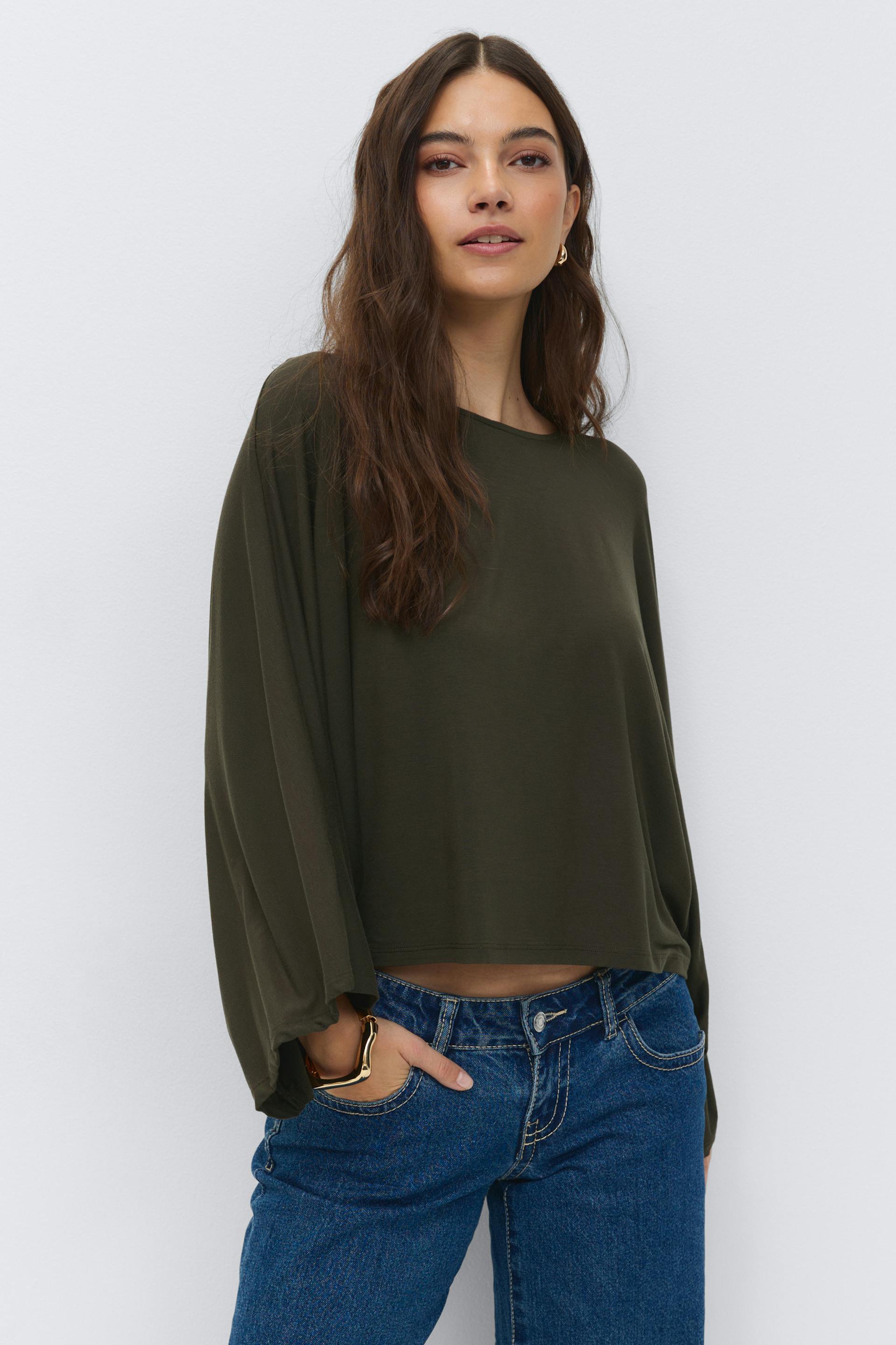 Oliivinvihreä, pitkähihainen, pitkähihainen, pallohihainen ja pääntie, joka on yhdistetty keskisinisiin, korkeavyötäröisiin farkkuihin, joissa on kontrastiompeleet; koristeena kultaiset korvakorut ja veistoksellinen kultamansetti.