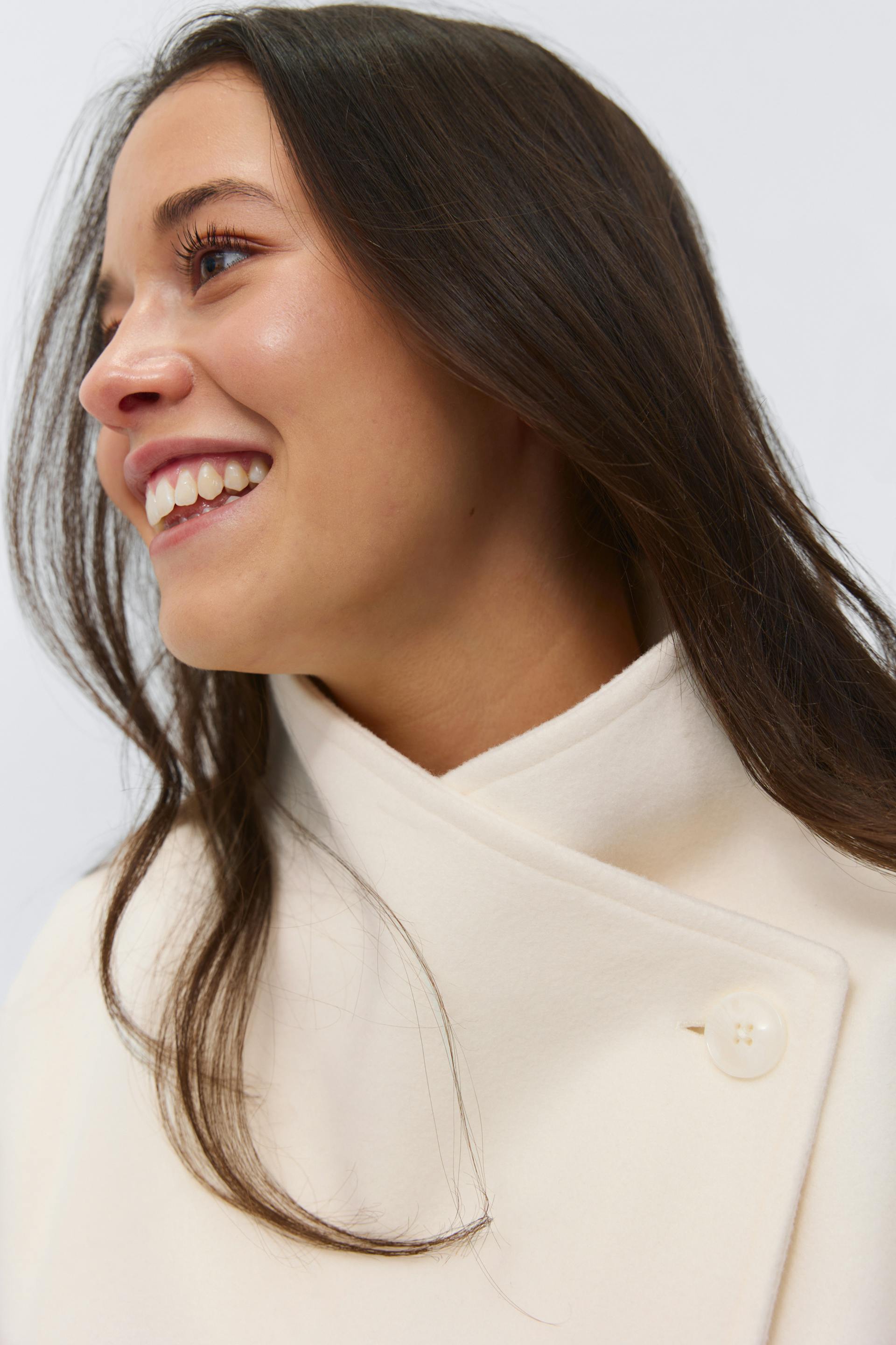 Cream ivory wrap-style high-neck coat in a wool-like fabric with a single visible shoulder button.