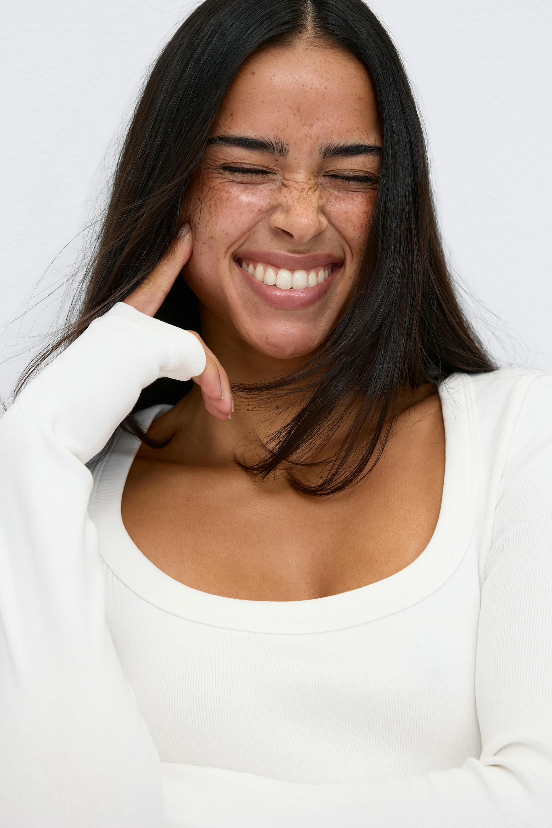Fitted white ribbed long-sleeve scoop-neck top with thumbhole cuffs.