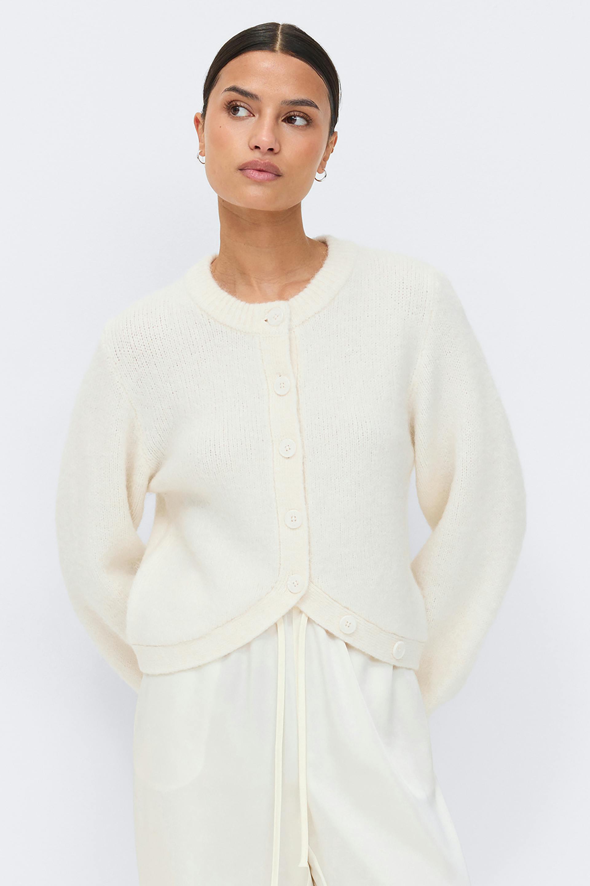 Ivory fuzzy knit button-front cardigan with ribbed round neckline and long sleeves, paired with ivory satin drawstring trousers.