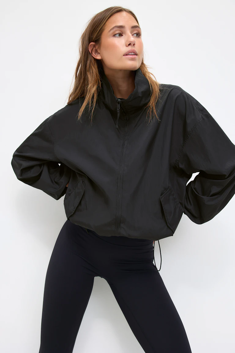 Svart croppad vindjacka med hög hals och dragkedja, överdimensionerade långa ärmar och fickor med lock fram, kombinerad med svarta leggings med hög midja.