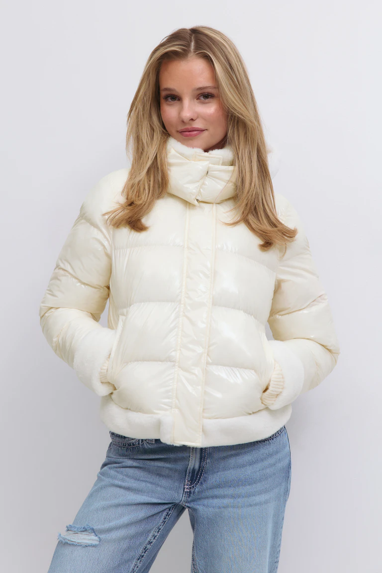 Krämfärgad, glansig pufferjacka med hög trattkrage, horisontell quiltning och plyschkant i ärmslut och nederkant, kombinerad med lätt tvättade, slitna jeans.