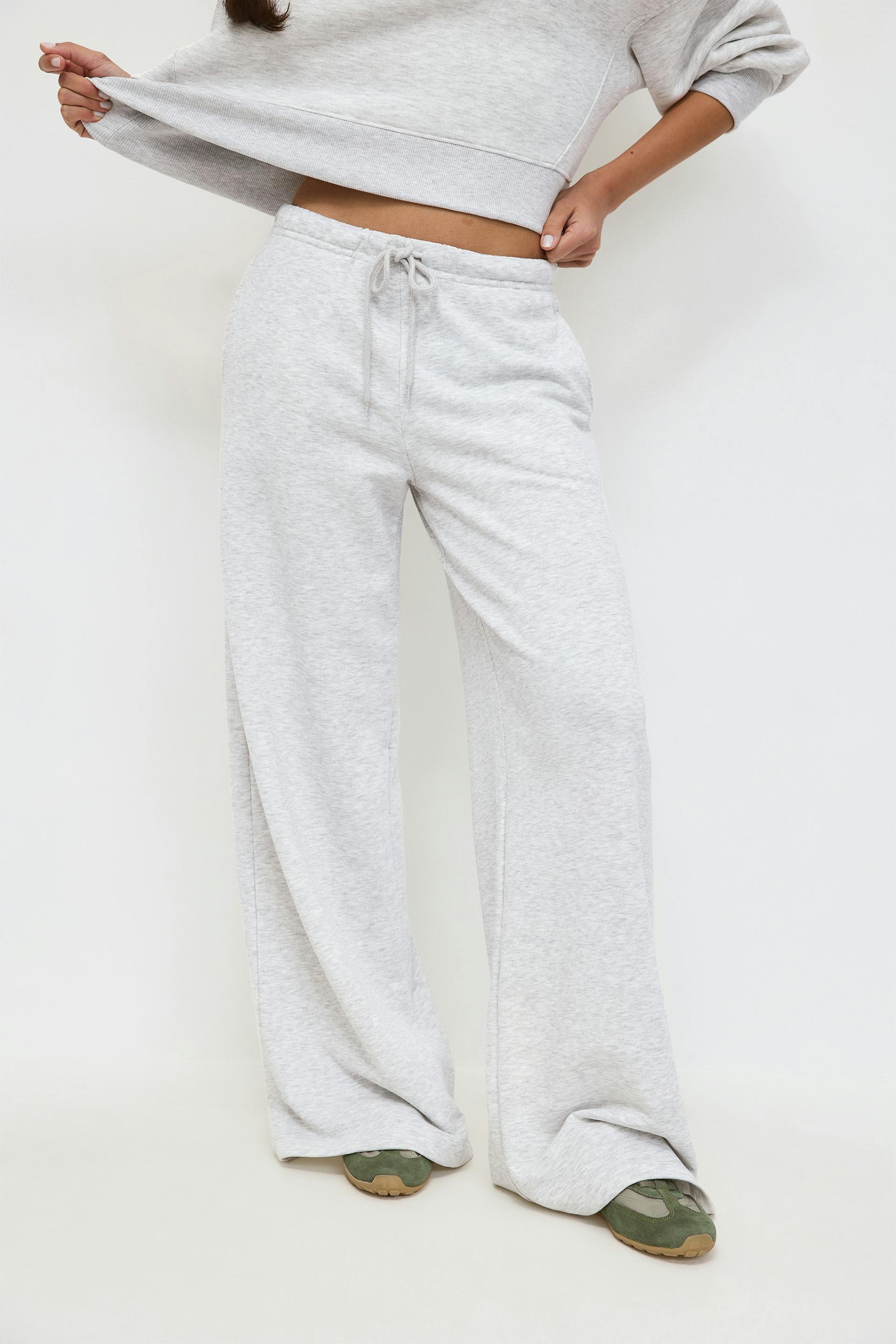 Black halter‑neck scoop‑front fitted tank top, light gray wide‑leg drawstring sweatpants with a matching gray sweatshirt tied at the waist, and leopard‑print ballet flats.