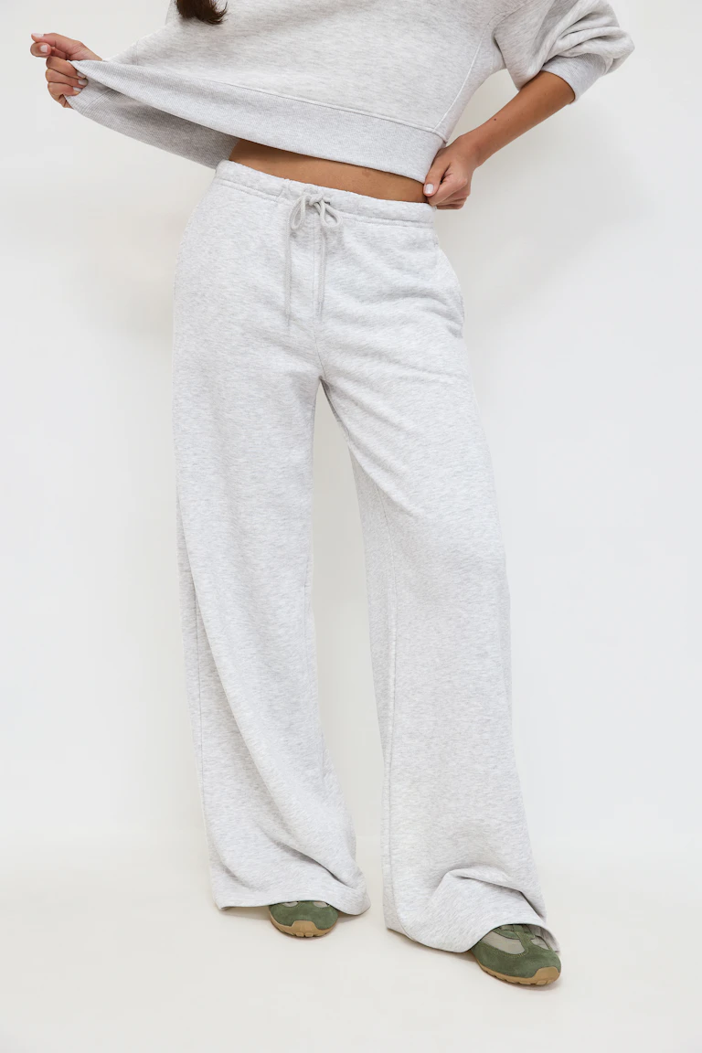 Svart linne med rund halsringning, ljusgrå sweatpants med vida ben och dragsko, matchande grå sweatshirt knuten i midjan och ballerinaskor med leopardmönster.