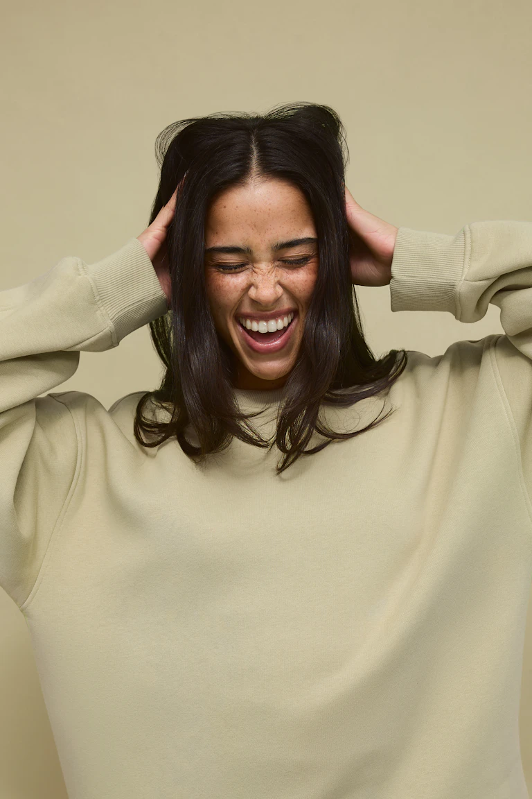 Vrouw draagt een oversized lichtbeige crewneck sweatshirt met geribde boorden.