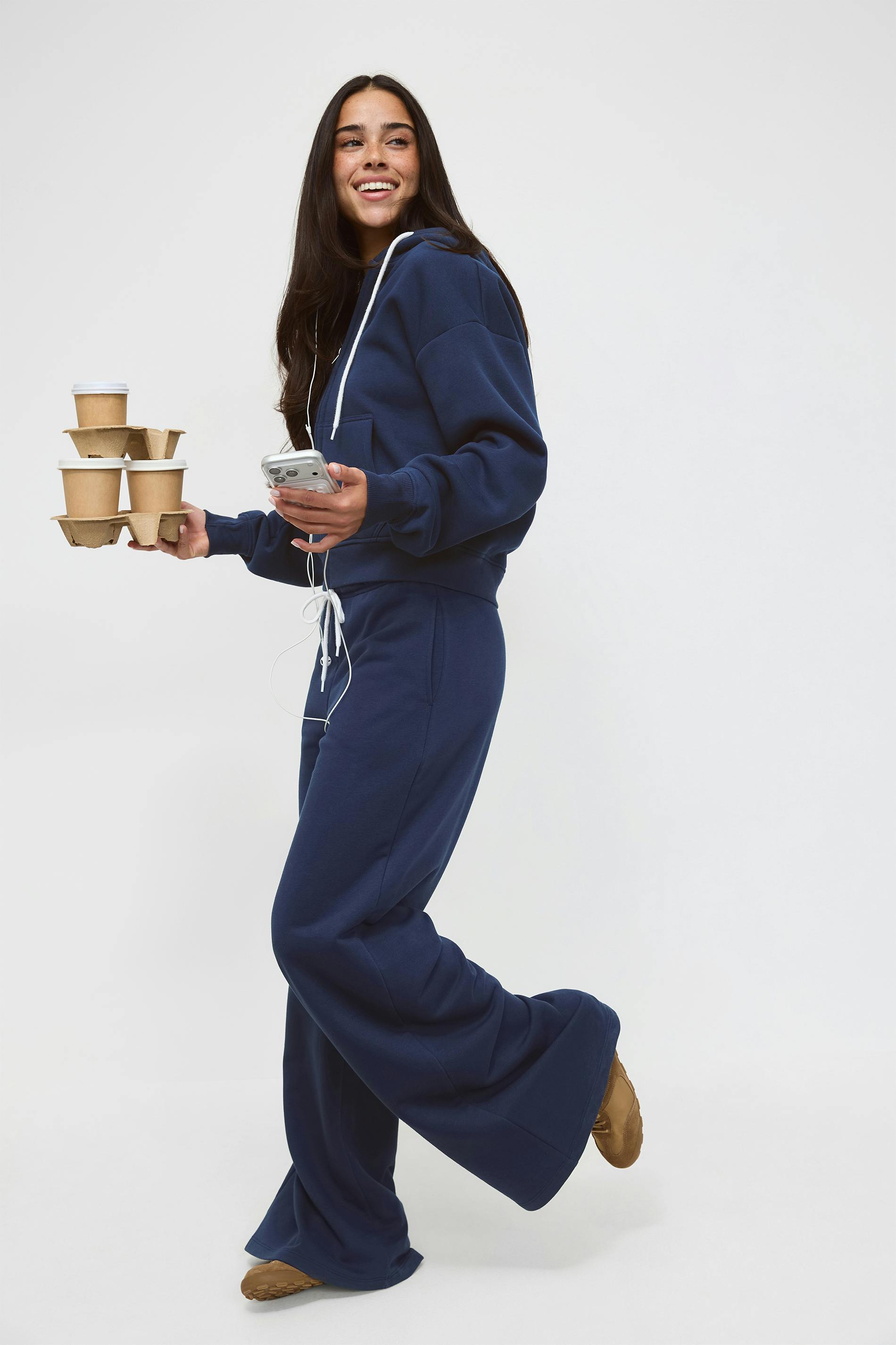 Marinblå huvtröja med dragkedja och vita snören, matchande marinblå sweatpants med snören, ett vinrött figurnära linne och svarta ballerinaskor.