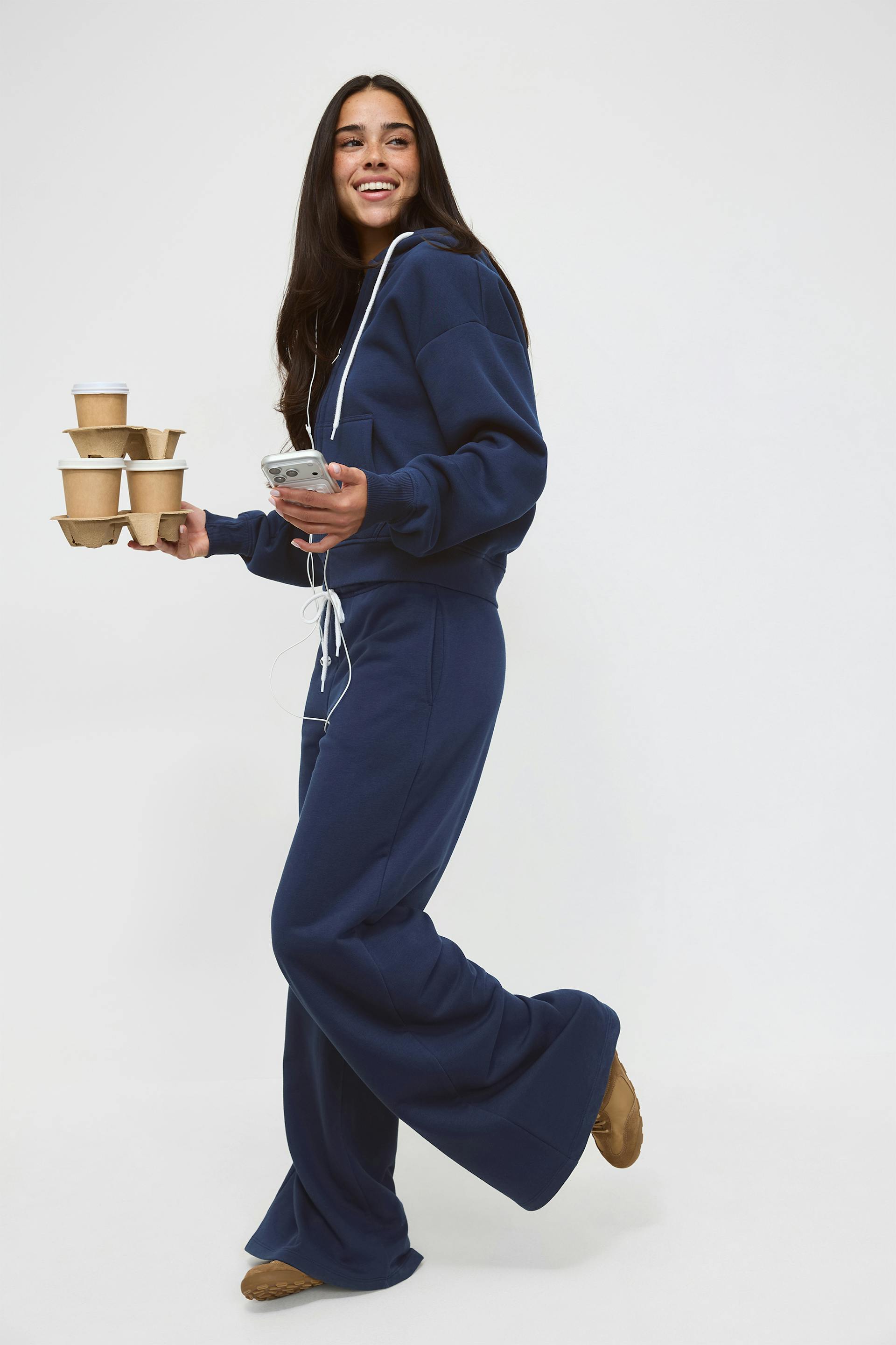 Marinblå huvtröja med dragkedja och vita snören, matchande marinblå sweatpants med snören, ett vinrött figurnära linne och svarta ballerinaskor.