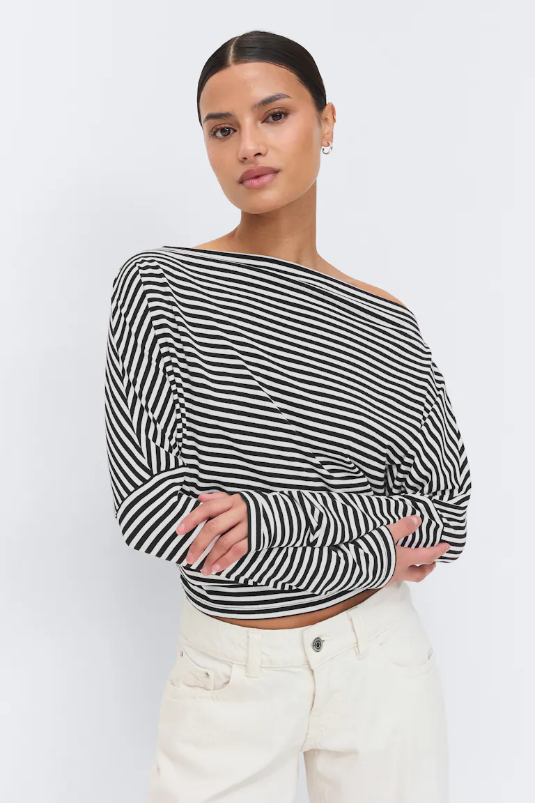 Svart-hvit, horisontalstripet, langærmet, langærmet topp uten skuldre kombinert med elfenbensjeans med høy midje.