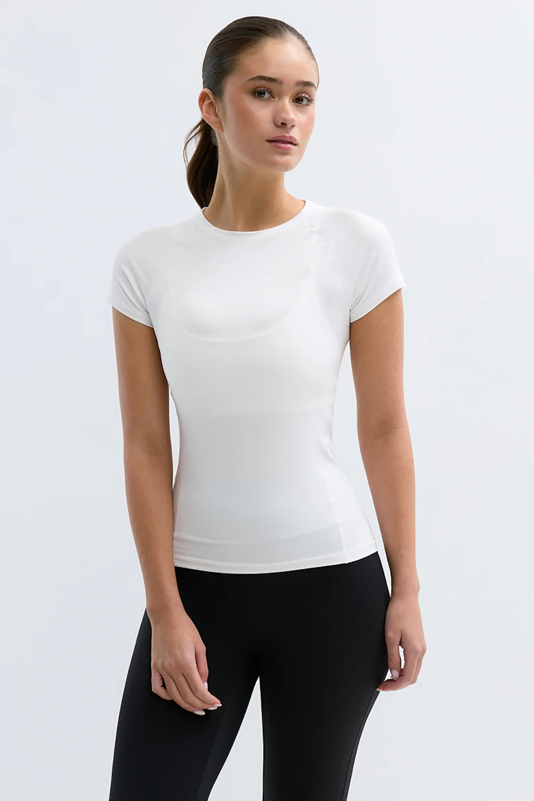 Haut athlétique blanc à manches courtes et col ras du cou, associé à un legging noir taille haute.