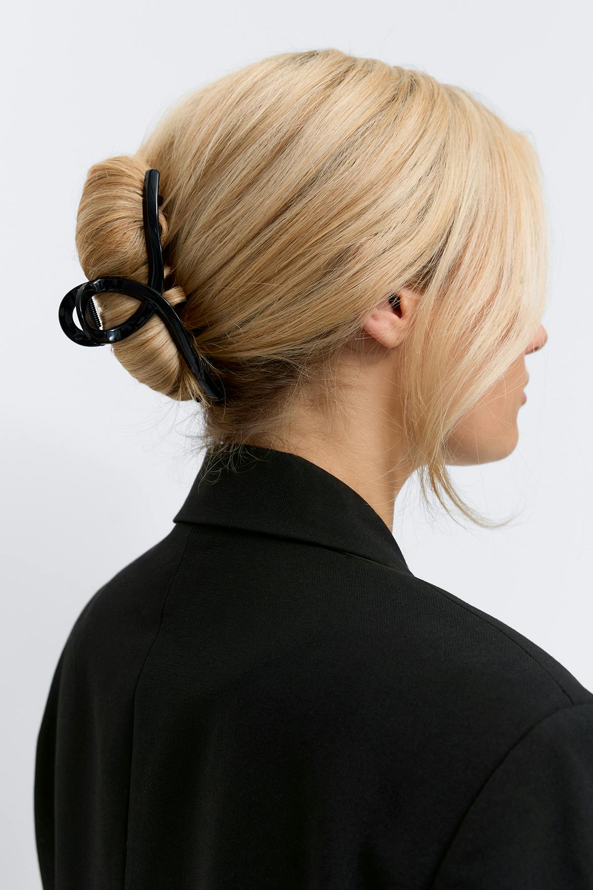 Black tailored blazer with notched collar; large glossy black hair claw securing the hair.