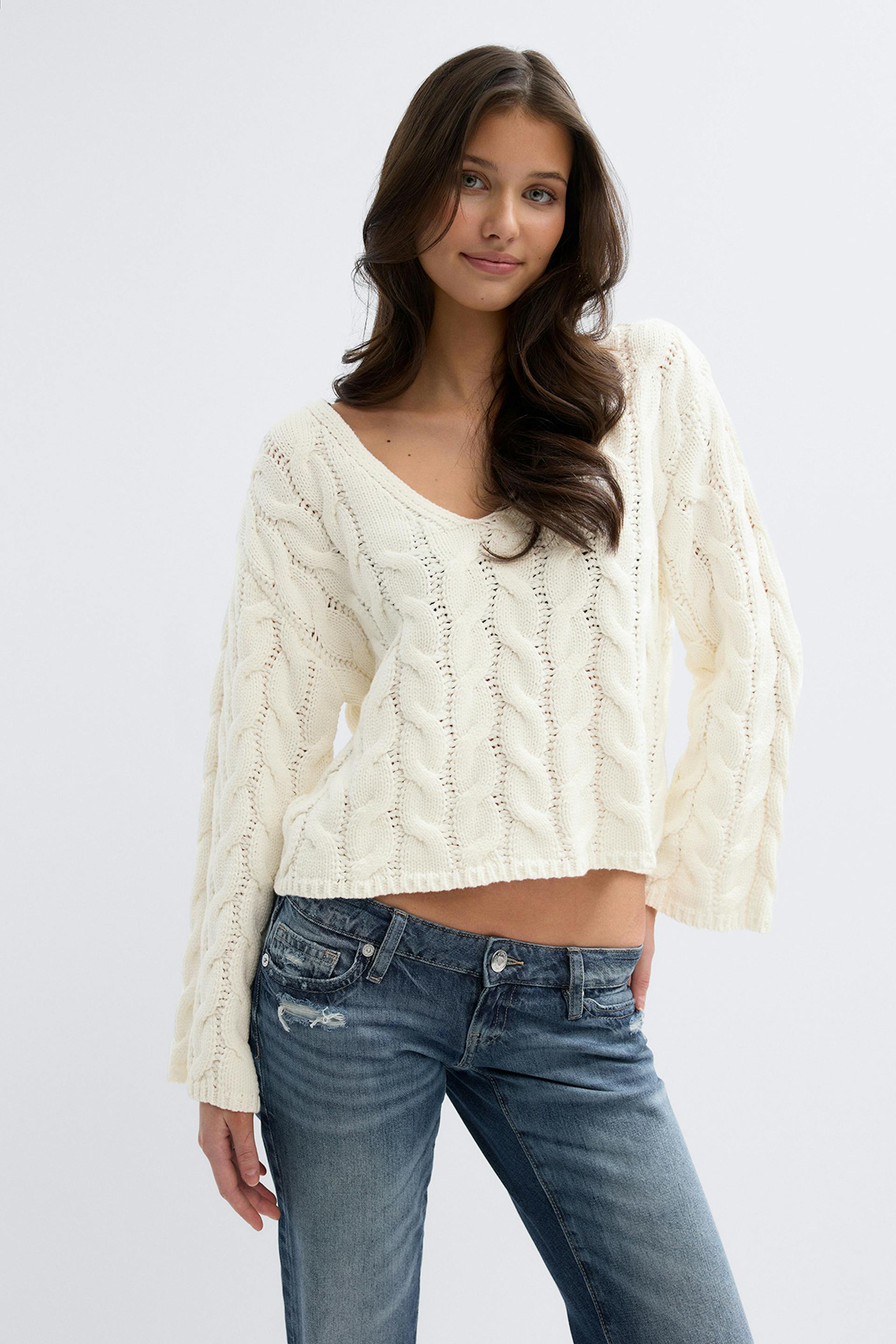 Norsunluunvärinen kaapelineulottu V-pääntie, pitkät hihat ja matalavyötäröiset, haalistuneet, siniset distressed-farkut.