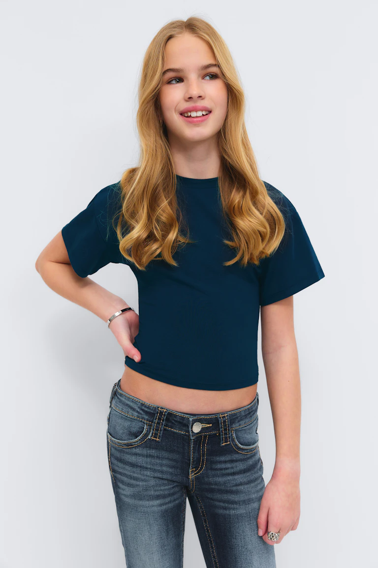 Tealfarbenes T-Shirt mit kurzen Ärmeln, gepaart mit einer verblassten, halbhohen Skinny-Jeans, dazu ein silberner Armreif und ein silberner Statement-Ring.