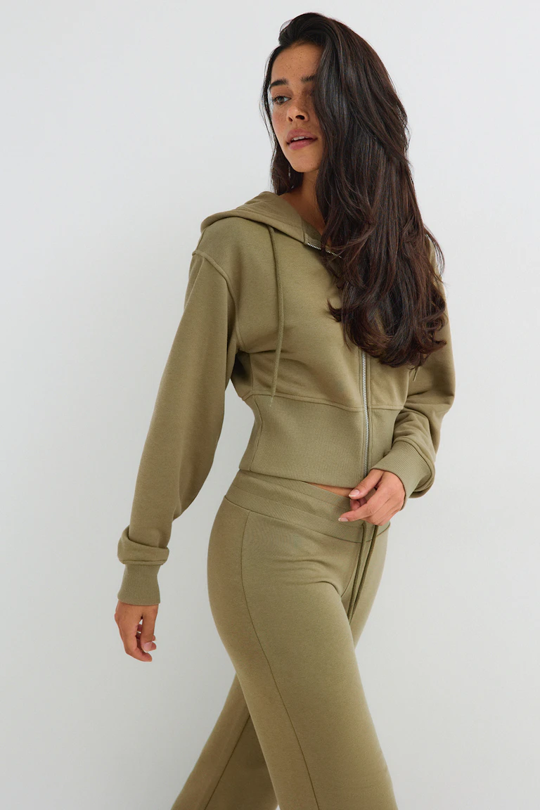 ID 345556, StyleColorSupplier 11519-E: Olivgrünes Sweatshirt mit Kapuze und Reißverschluss sowie dazu passende Hose mit weitem Bein.