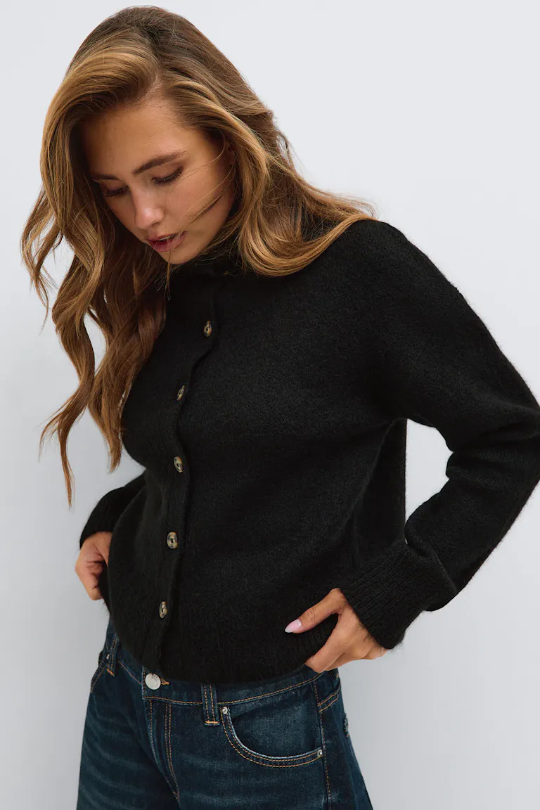 Schwarze Strickjacke mit Knopfleiste und dunkelblaue Jeans.