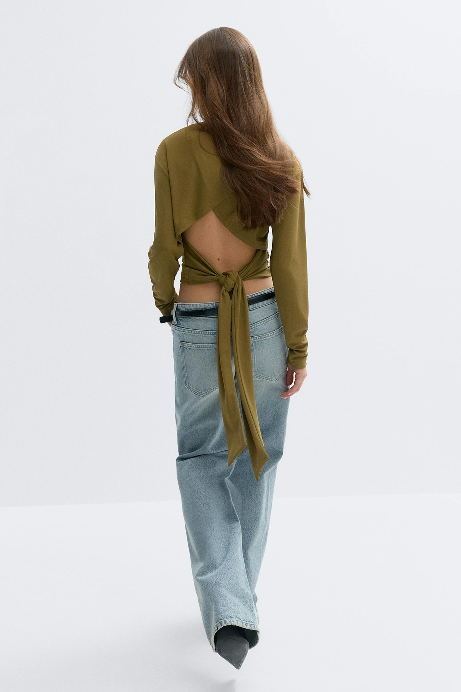 Oliivinvihreä, pitkähihainen, selkä menosuuntaan avonainen kietaisutoppi, jossa on solmittava vyötärö, yhdistettynä vaaleanvihreisiin, väljästi istuviin farkkuihin ja mustiin teräväkärkisiin nilkkasaappaisiin.