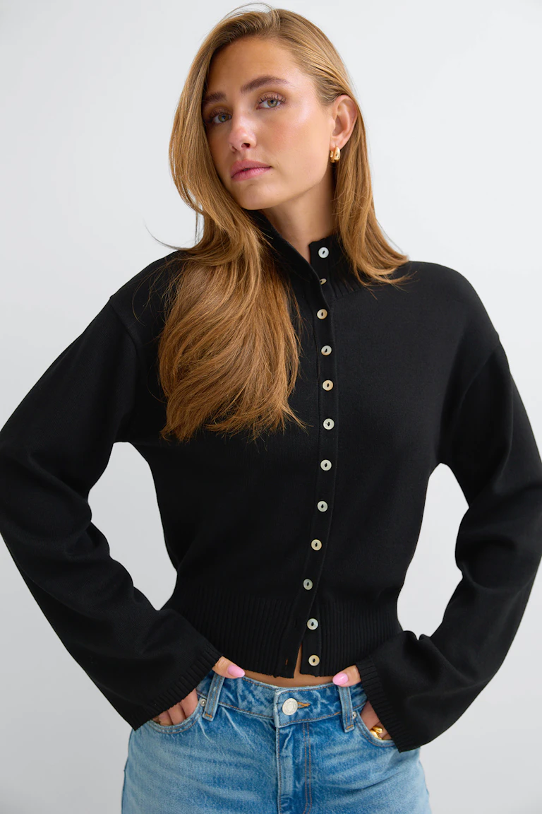 id: 321379 | StyleColorSupplier: 17490 | Svart kofta med knappar framtill, långa ärmar och ribbad nederkant, stylad med ljusblå jeans.