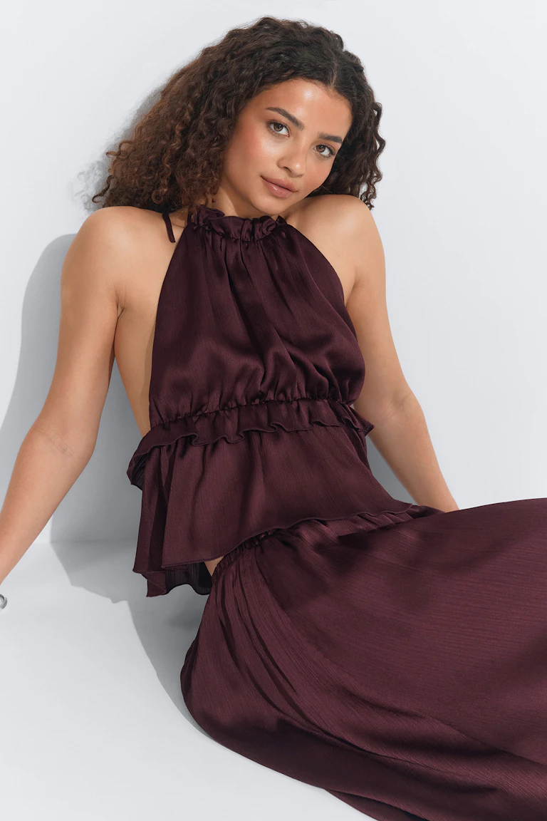 Burgundy satin halter top with gathered neckline and ruffled tier detailing, paired with a matching flowing maxi skirt.