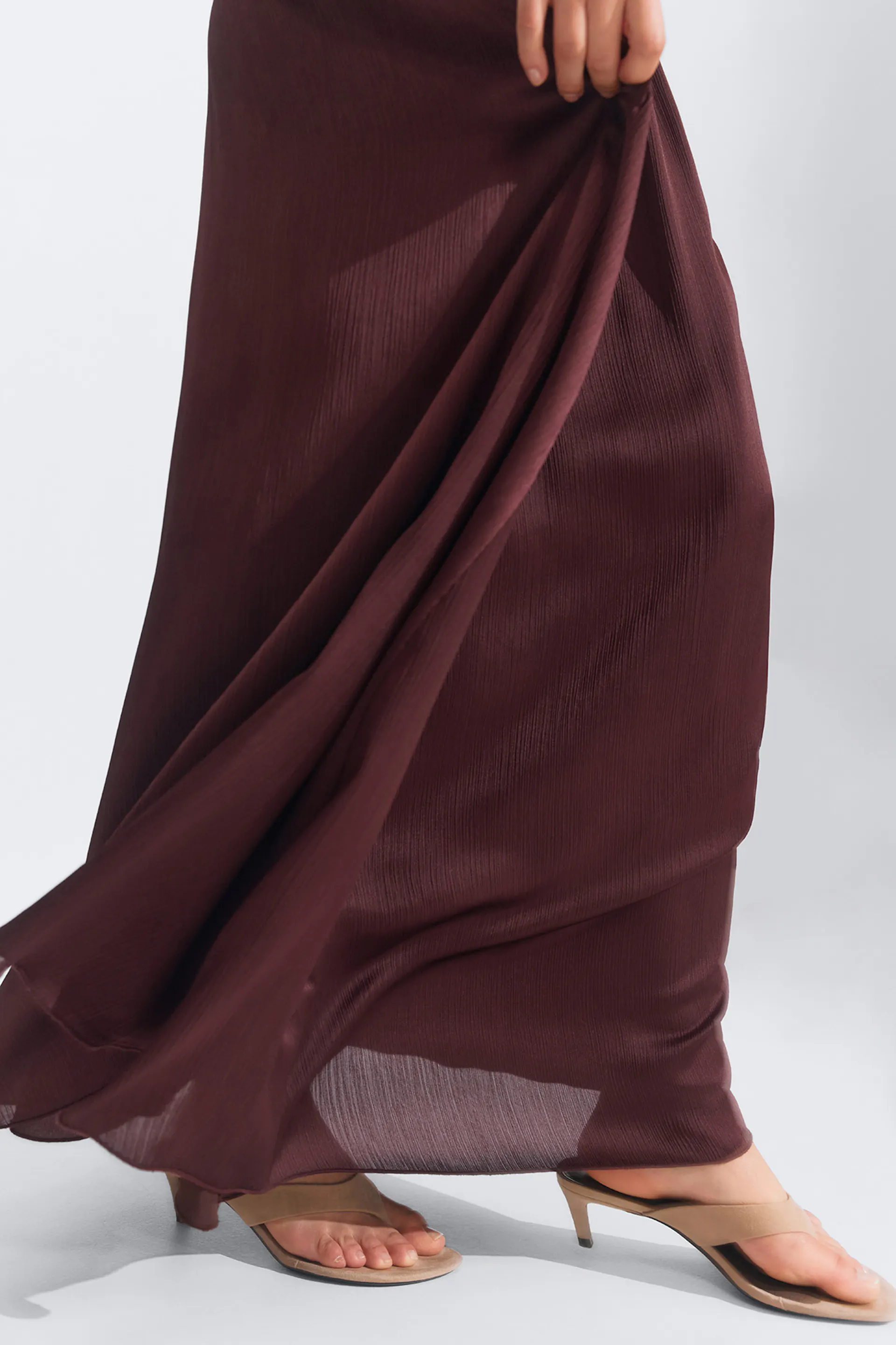 Jupe plissée bordeaux, longueur de plancher, associée à des mules à bout ouvert beige.