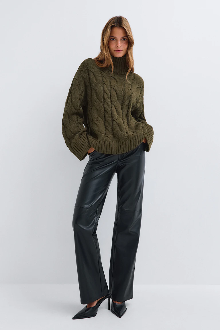 Pull à col roulé vert olive à mailles torsadées, porté avec un jean bleu clair.