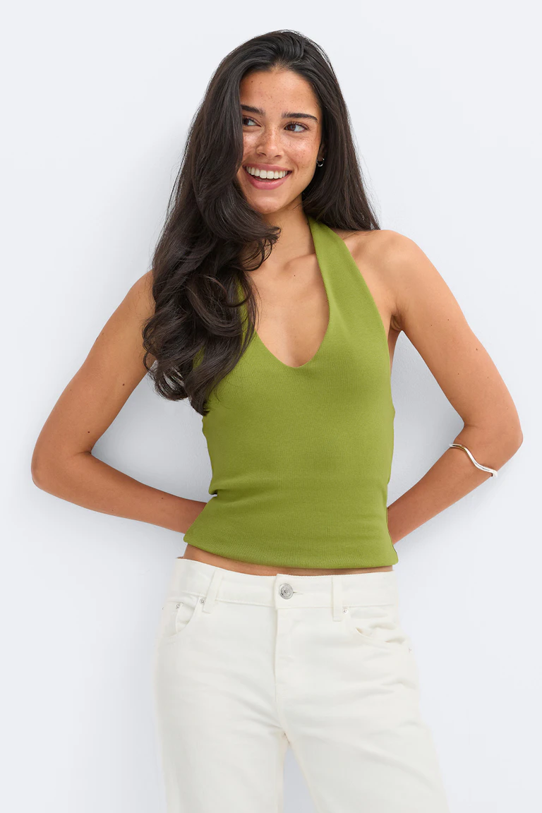 En limegrøn, ribbet halterneck-top med dyb V-udskæring, kombineret med højtaljede, off-white jeans.