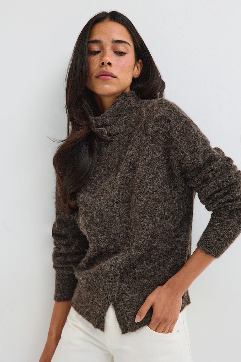 Braune, flauschige Strickjacke mit Knöpfen, kombiniert mit einer weißen Hose.