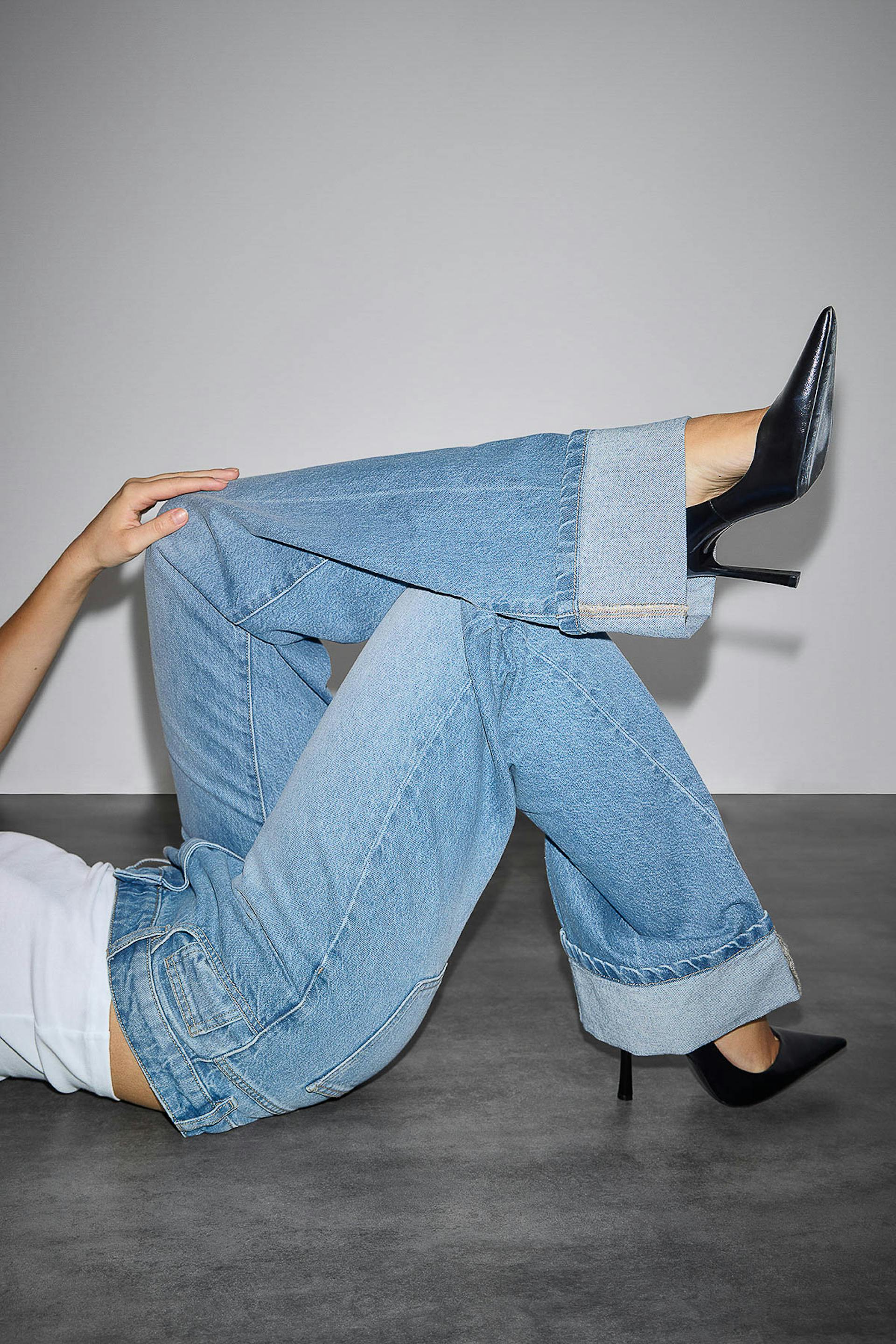 Débardeur blanc ajusté, jean large à revers délavé et talons aiguilles noirs.