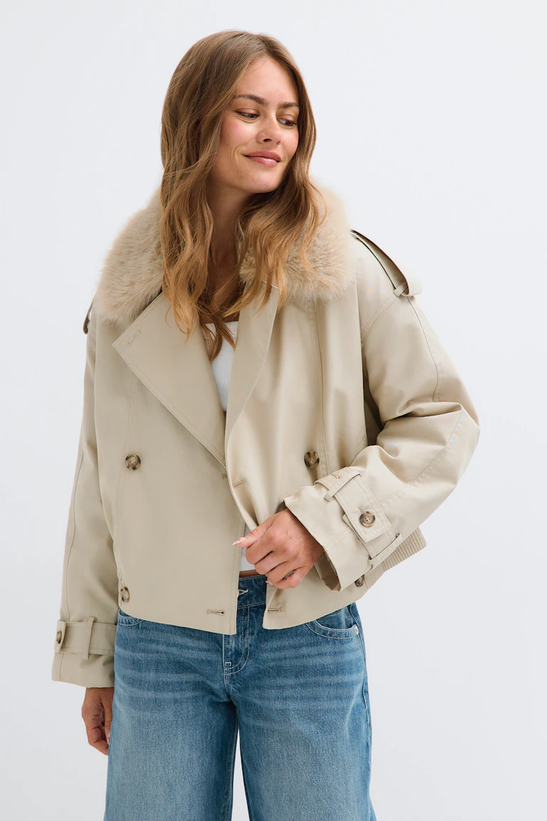 Beige trench jacket with a faux-fur collar, paired with a white top and blue jeans.