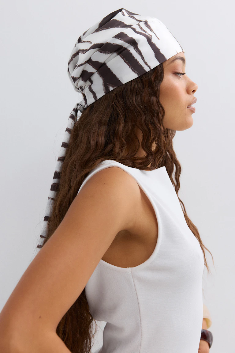 White sleeveless fitted top paired with a white headscarf featuring irregular dark‑brown stripes, tied at the back.