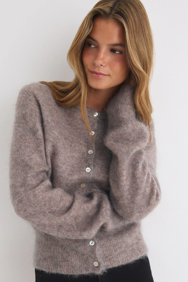 Taupefarbene, flauschige Strickjacke mit Knopfleiste und schwarzer Hose.