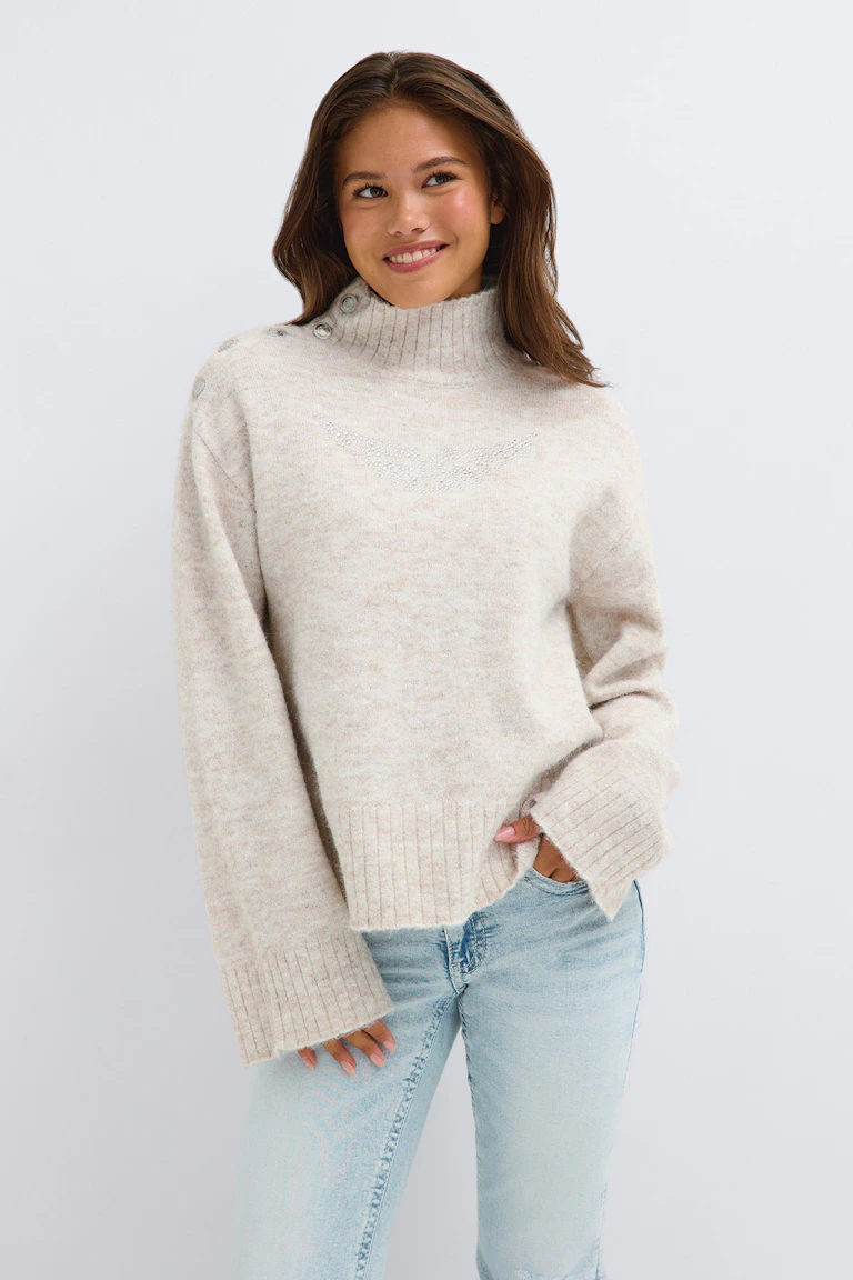 ID 319848, StyleColorSupplier 17490: Cremefarbener, gerippter Rollkragenpullover mit Knopfdetails an den Schultern und hell gewaschenen Jeans.