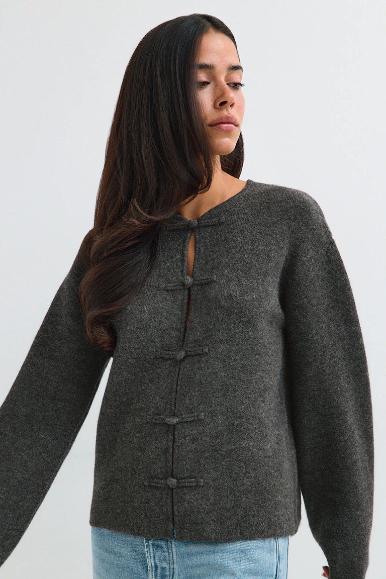 Dunkelgraue Strickjacke mit Knopfleiste, kombiniert mit hellblauen Jeans.
