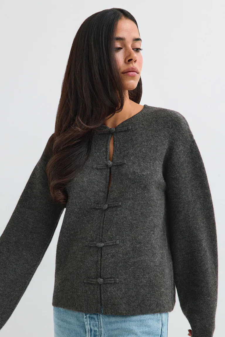 Dunkelgraue Strickjacke mit Knopfleiste, kombiniert mit hellblauen Jeans.