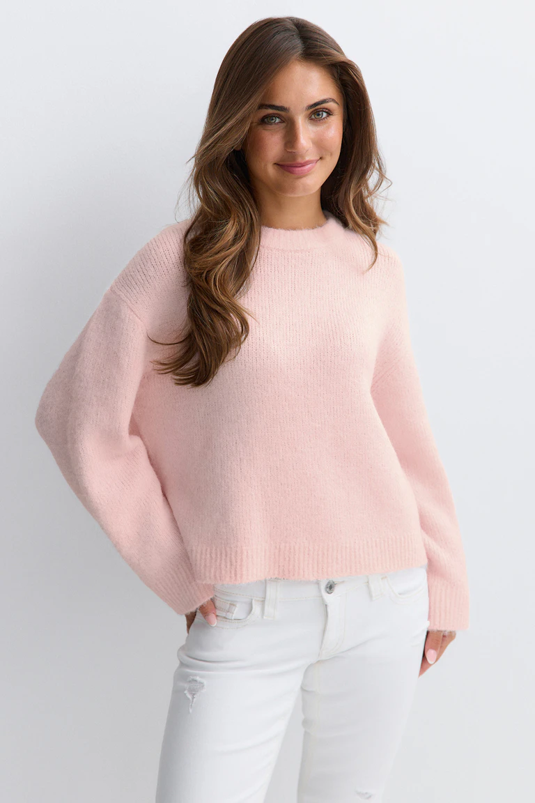 Ljusrosa, luddig tröja med rund hals, långa ärmar och ribbade nederkanter och ärmslut, i kombination med vita, figursydda jeans med diskreta slitningar.