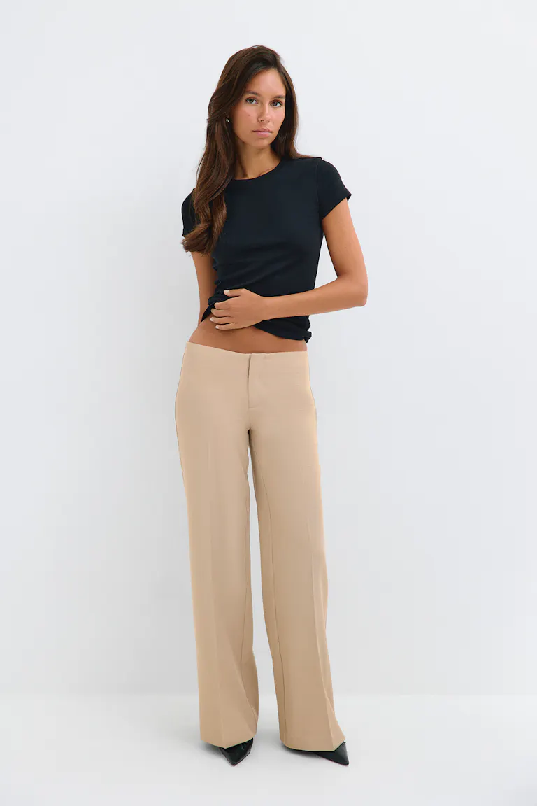 Black fitted short-sleeve top with beige wide-leg trousers.
