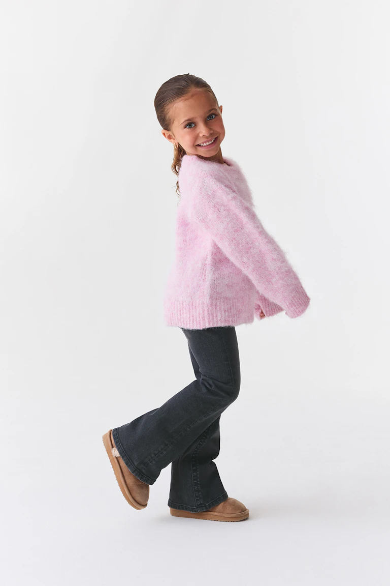 ID 324250, StyleColorSupplier 19021: Een zachte roze trui, een donkere flared-jeans en bruine suède laarzen.