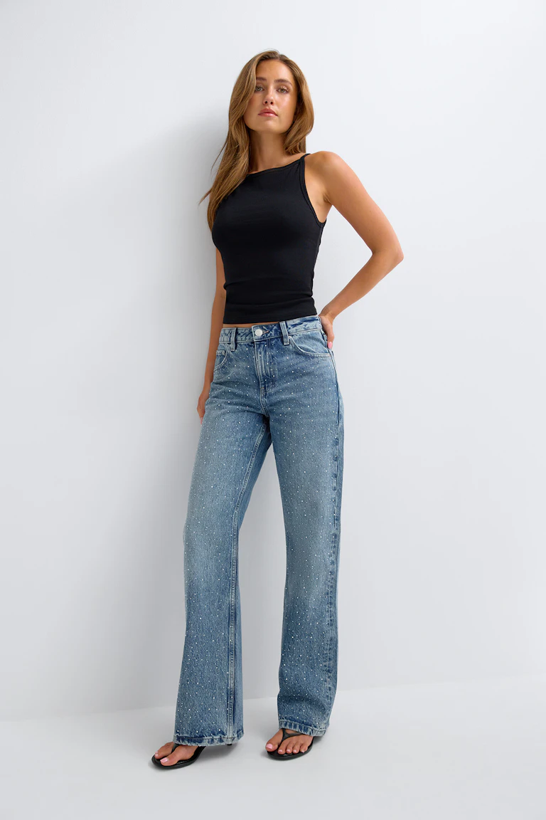 Schwarzes, ärmelloses Oberteil und verzierte Jeans mit weitem Bein.