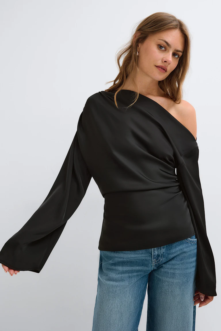 ID 322396, StyleColorSupplier 14423: zwarte top met één schouderband en lange, uitlopende mouwen, gecombineerd met een blauwe spijkerbroek.