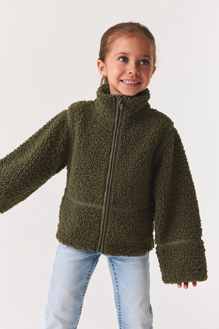 Veste zippée en polaire « teddy » vert olive, associée à un jean délavé clair.