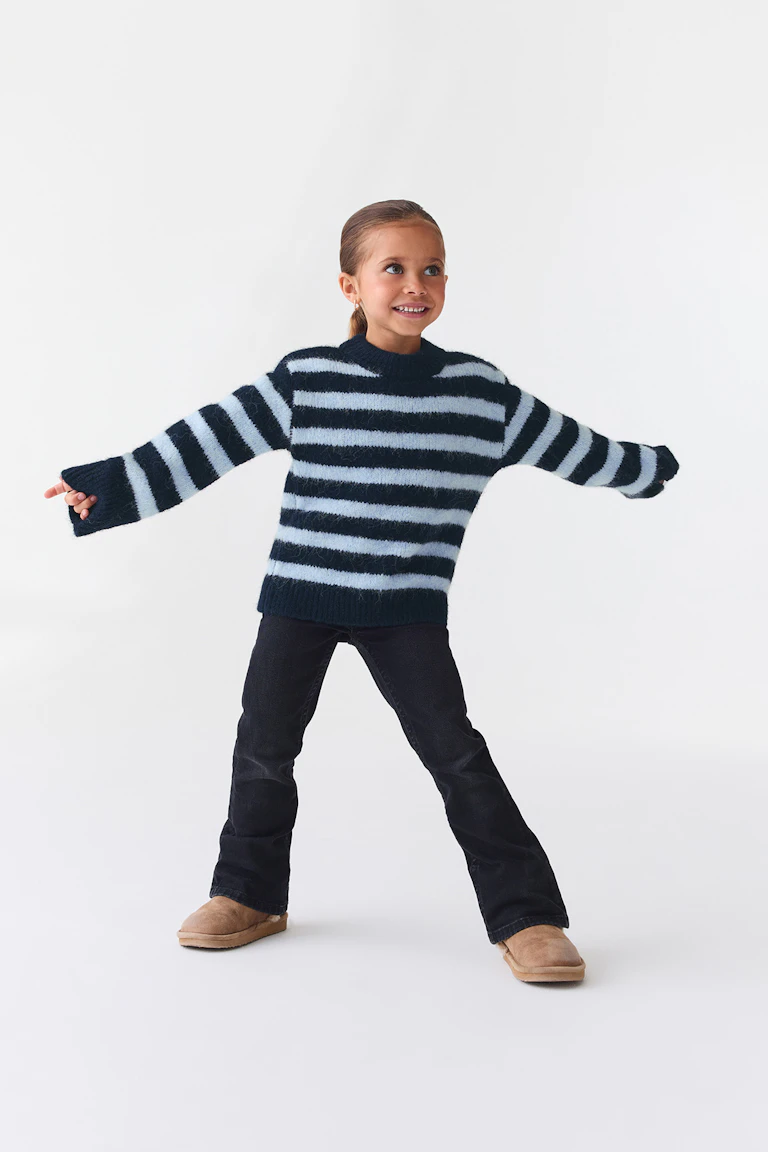 En marineblå og lyseblå stripete genser, mørke jeans og beige slip-on-støvler.