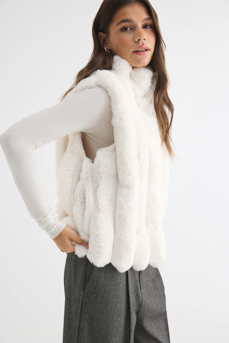 328531, StyleColorSupplier 14651: Hvid vest i imiteret pels over en cremefarvet langærmet bluse og grå bukser.