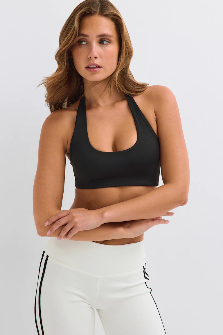 Svart sport-BH med halterneck och vita leggings med svarta sidoränder.