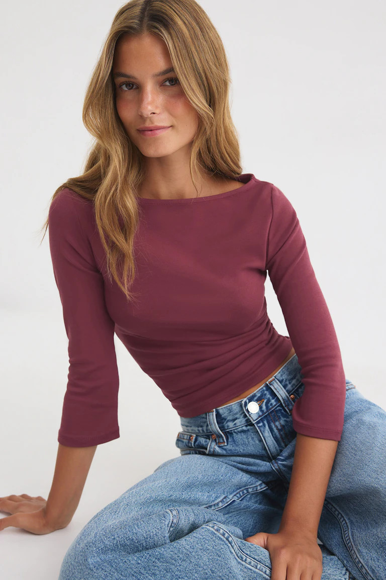 ID 348497, StyleColorSupplier 16547: burgunderrotes, figurbetontes Langarm-Oberteil mit hellblauen Jeans mit hoher Taille.
