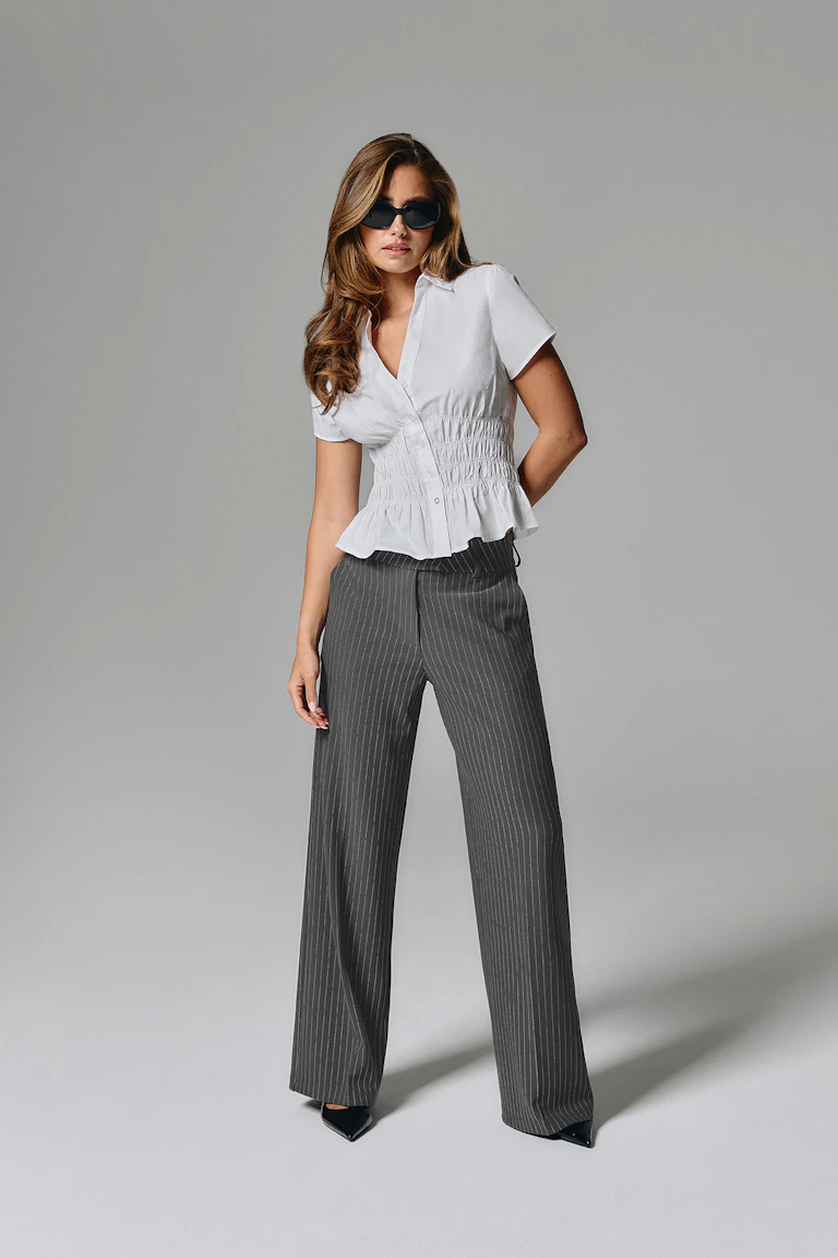 ID 332718, StyleColorSupplier 14651: Hvit peplum-bluse med korte ermer, mørke bukser med brede ben og mørke, smale striper samt svarte spisse hæler.