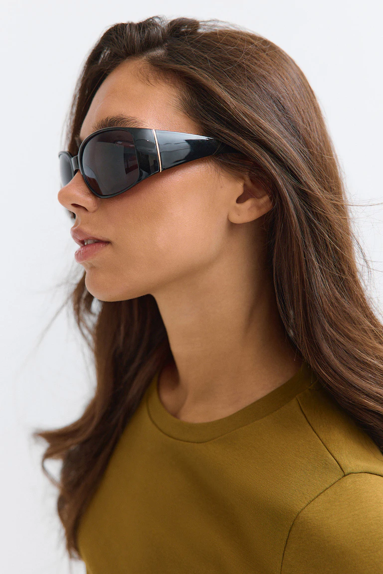 Black wraparound sunglasses and an olive-green crew-neck top.