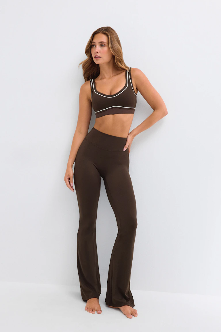 Dunkelbrauner Sport-BH mit weißem Besatz und dazu passenden, hoch taillierten, ausgestellt geschnittenen Leggings.