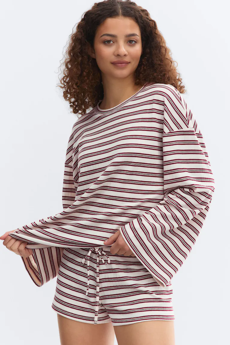 Creme- und bordeauxfarbenes, horizontal gestreiftes, langärmeliges Oberteil mit Rundhalsausschnitt und weiten Glockenärmeln, gepaart mit passenden Shorts mit Kordelzug.