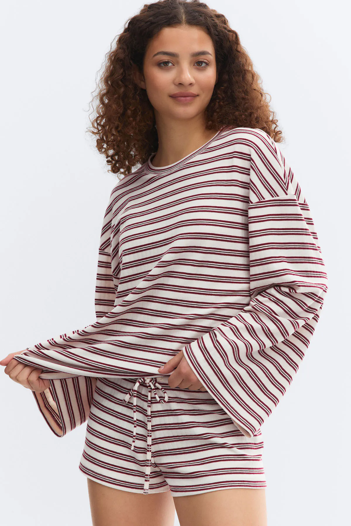 Cream-and-burgundy horizontal striped crewneck long-sleeve top with wide bell sleeves, paired with matching drawstring shorts.