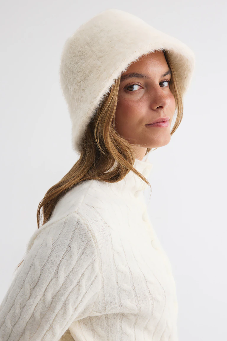 Cream fluffy hat and matching cable-knit sweater.